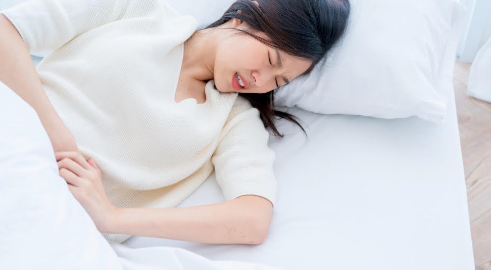 asian-woman-with-menstrual-problems-young-woman-with-stomach-ache-lying-bedlying-bed-holding-her-stomach