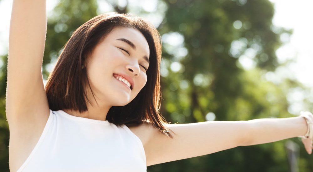 close-up-asian-woman-stretching-hands-up-smiling-walking-park-looking-carefree-happy