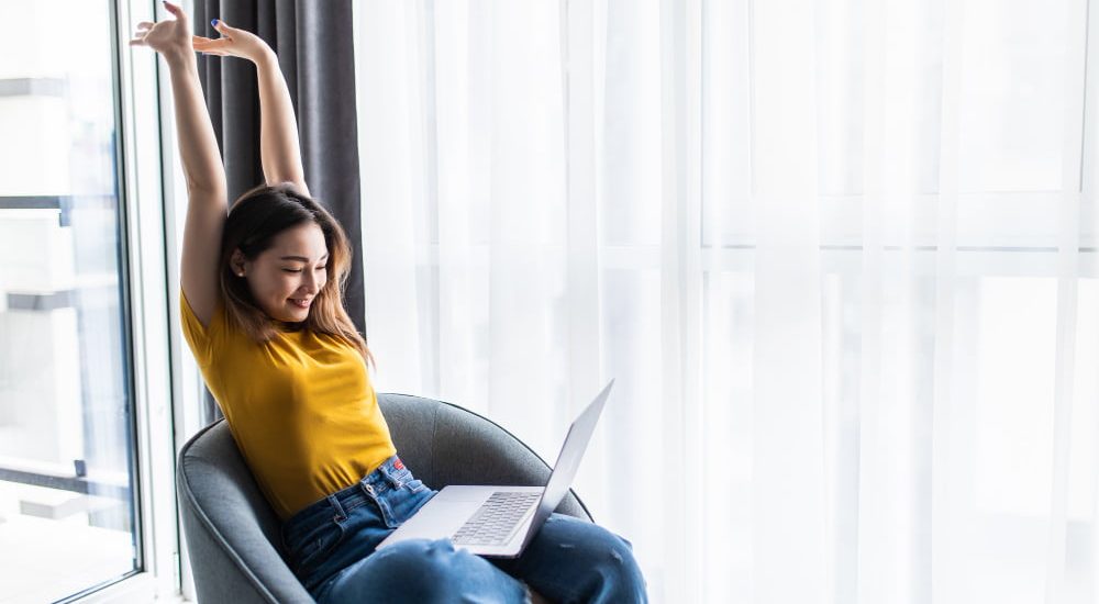 happy-relaxed-casual-woman-sitting-chair-with-laptop-front-her-stretching-her-arms-her-head
