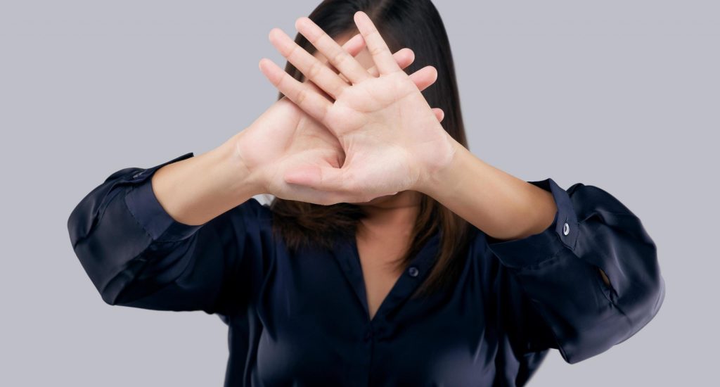 woman-in-black-suit-showing-her-denial-with-no-on-her-hand-against-gray-background